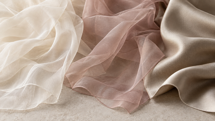Silk chiffon, polyester chiffon and silk twill swatches arranged to compare sheerness, drape and surface